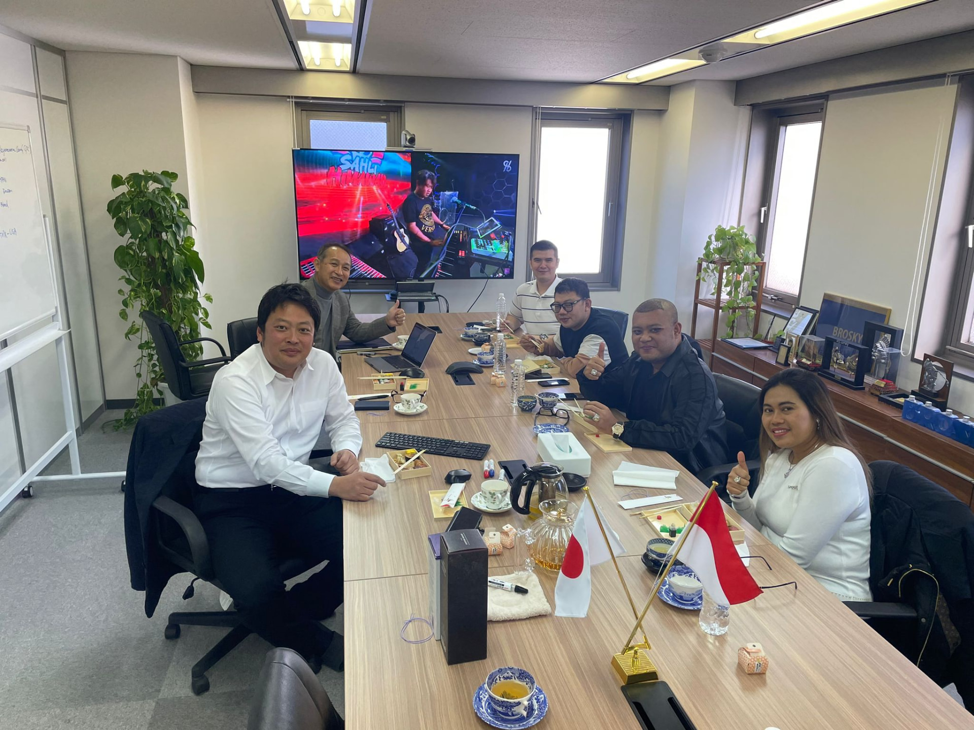 Welcoming an Indonesian delegation to the Tokyo office — Japan and Indonesia flags on the table, business discussed over lunch.