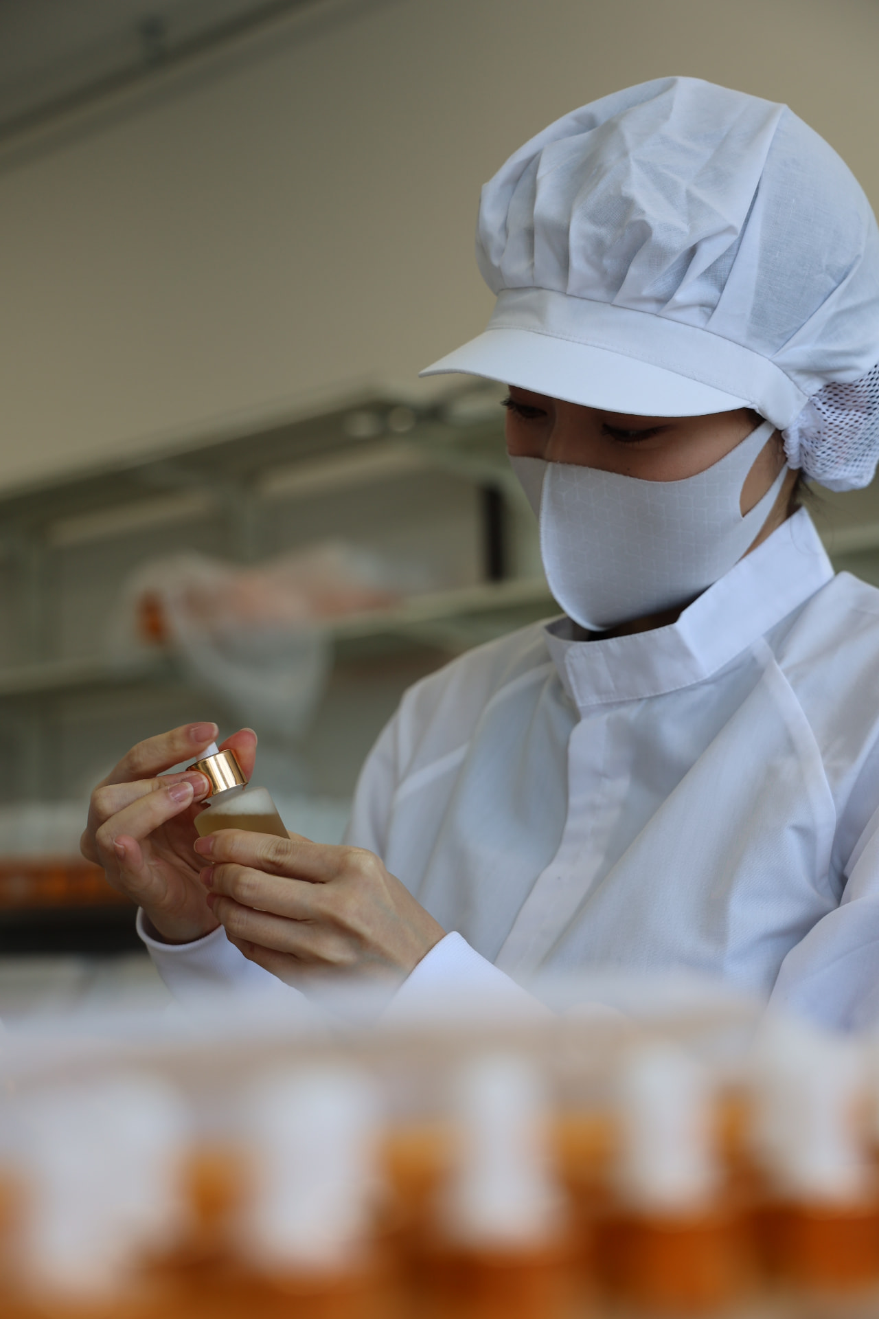 A team member checks a filled bottle on the cosmetics production line.